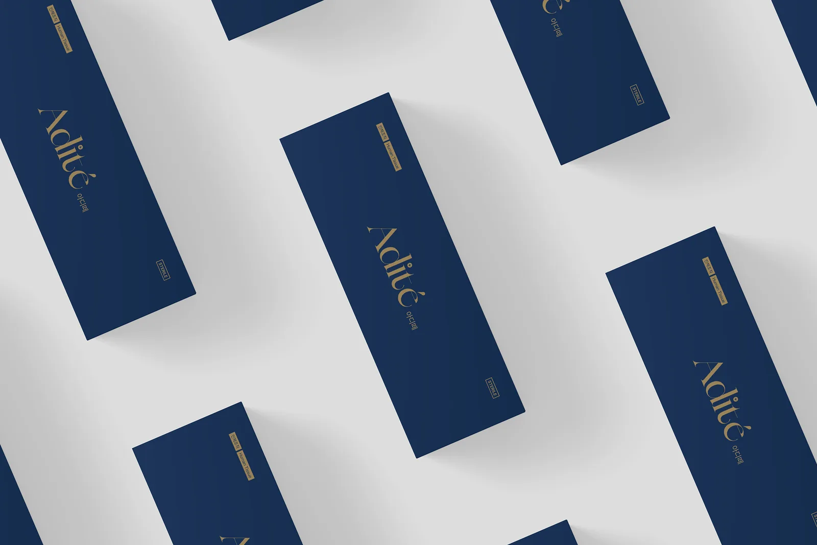Repeating pattern of navy and gold Adité product cartons on a light grey surface