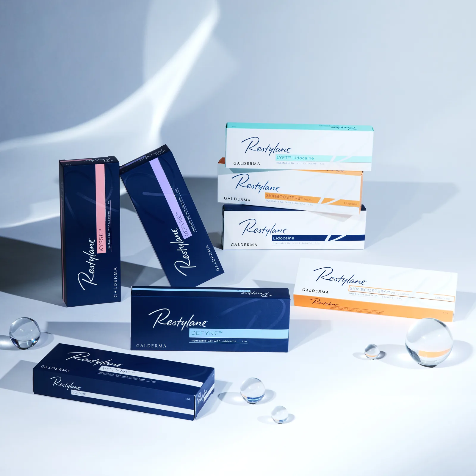 Restylane Kysse, Defyne, Refyne, Lyft, Volyme and Skinboosters cartons arranged with glass spheres in daylight