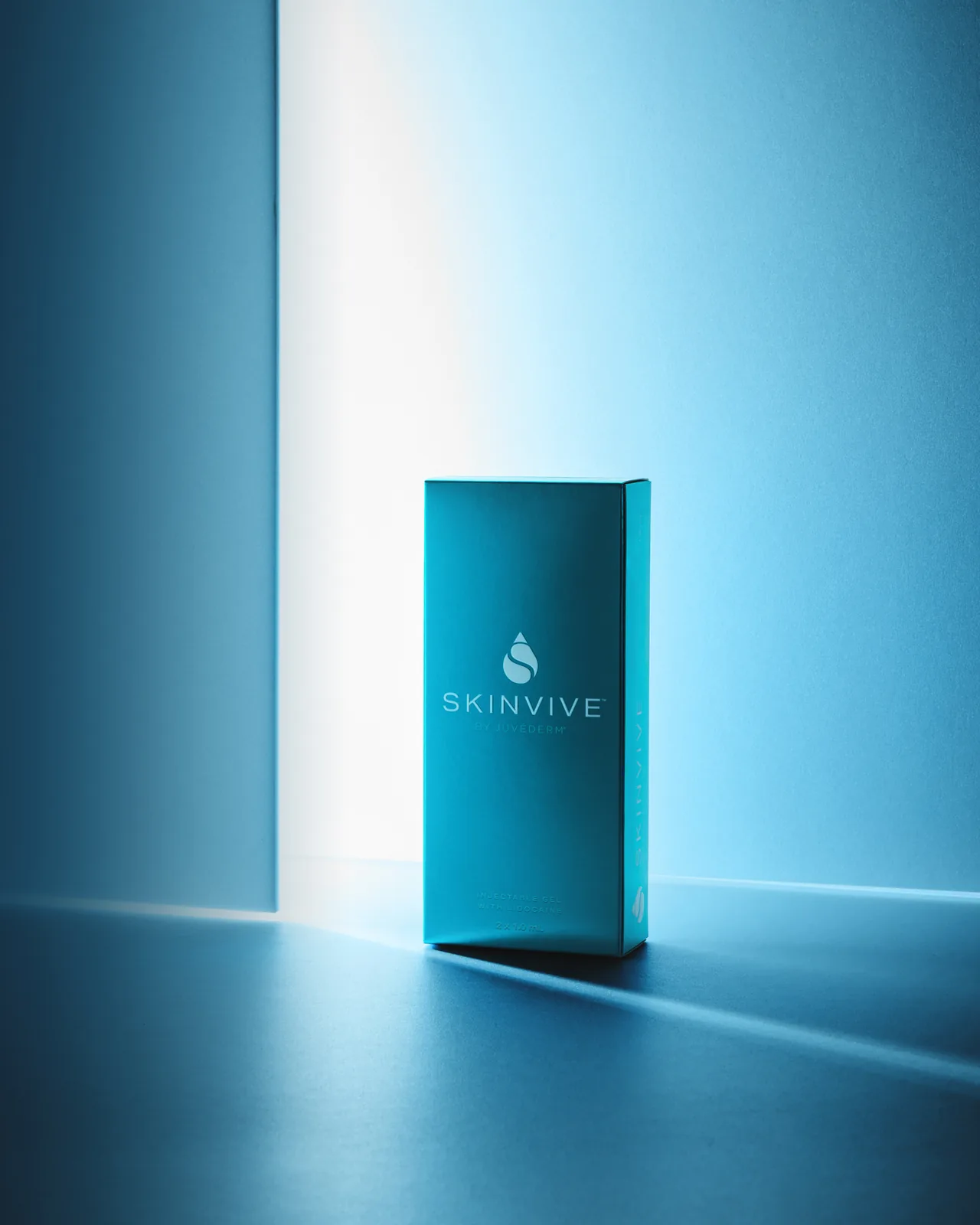 Skinvive by Juvederm carton lit by a shaft of light against a deep blue backdrop