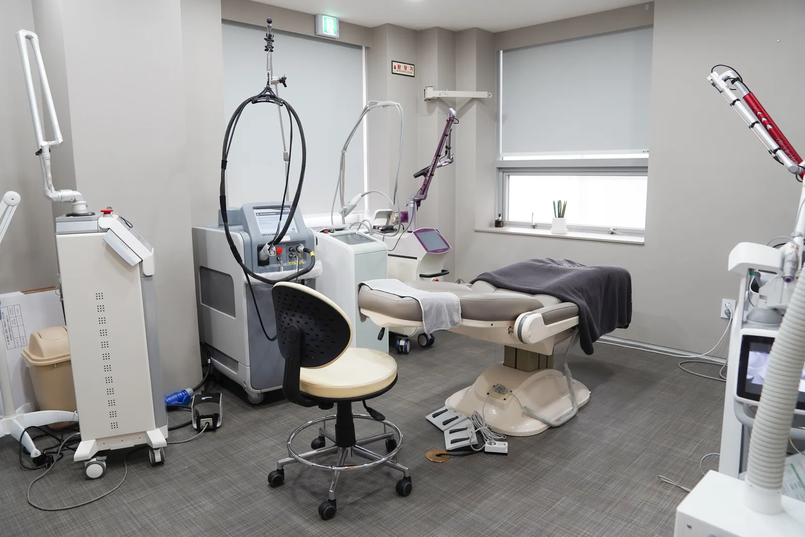 Laser treatment room at Dear Clinic Cheongdam with several laser platforms and a powered treatment chair