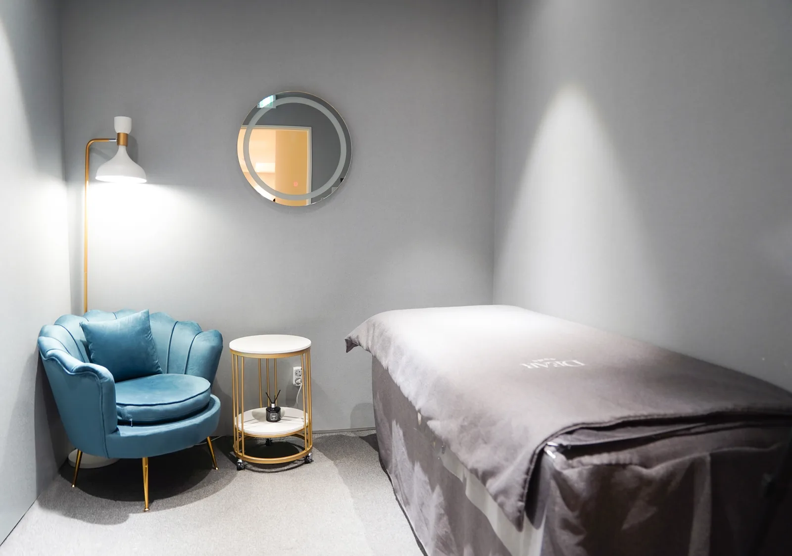 VIP single treatment room with a blue velvet armchair and gold side table at Dear Clinic Cheongdam