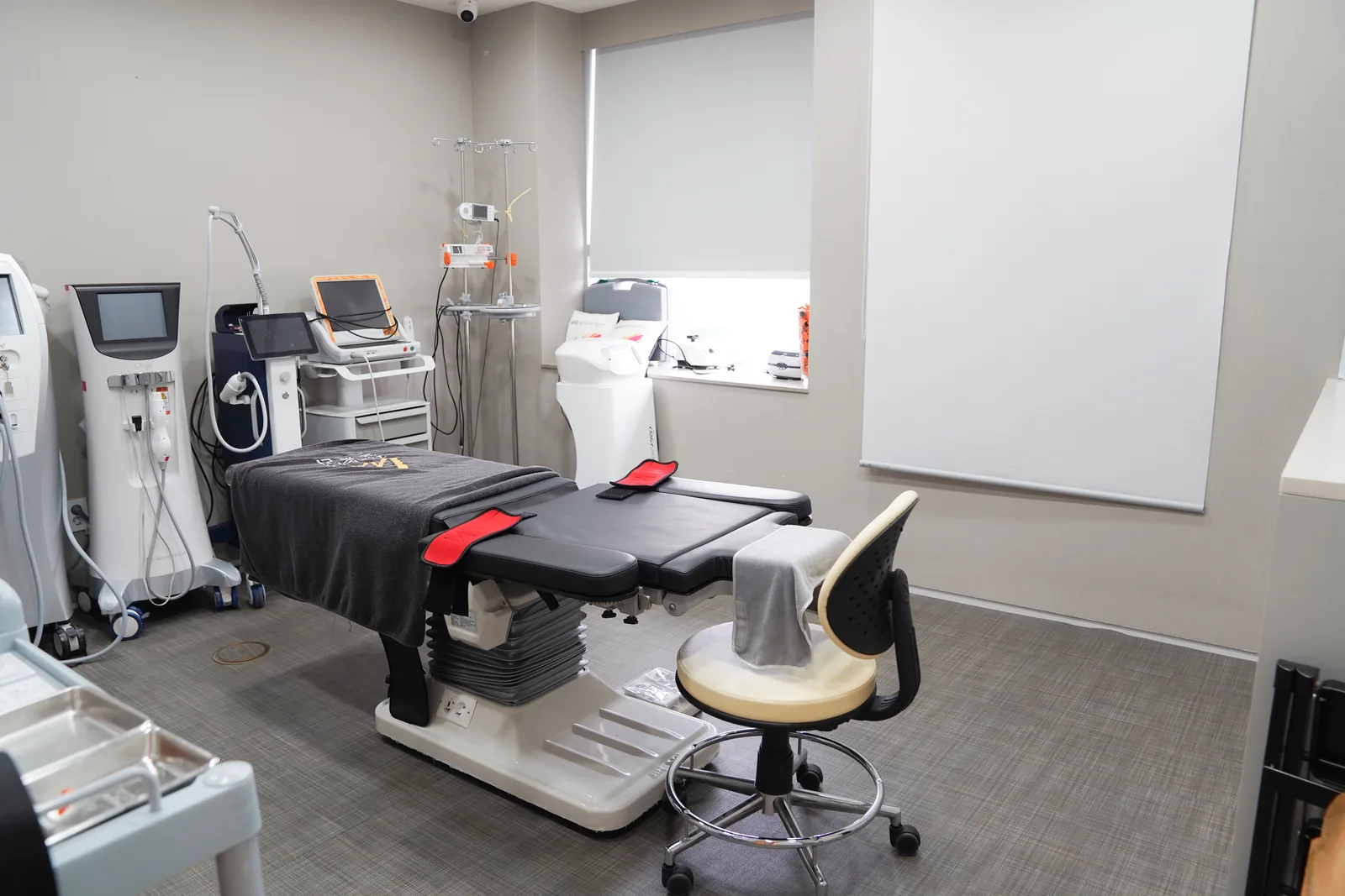 Procedure room with a powered treatment table, IV stand and infusion pump at Dear Clinic Cheongdam