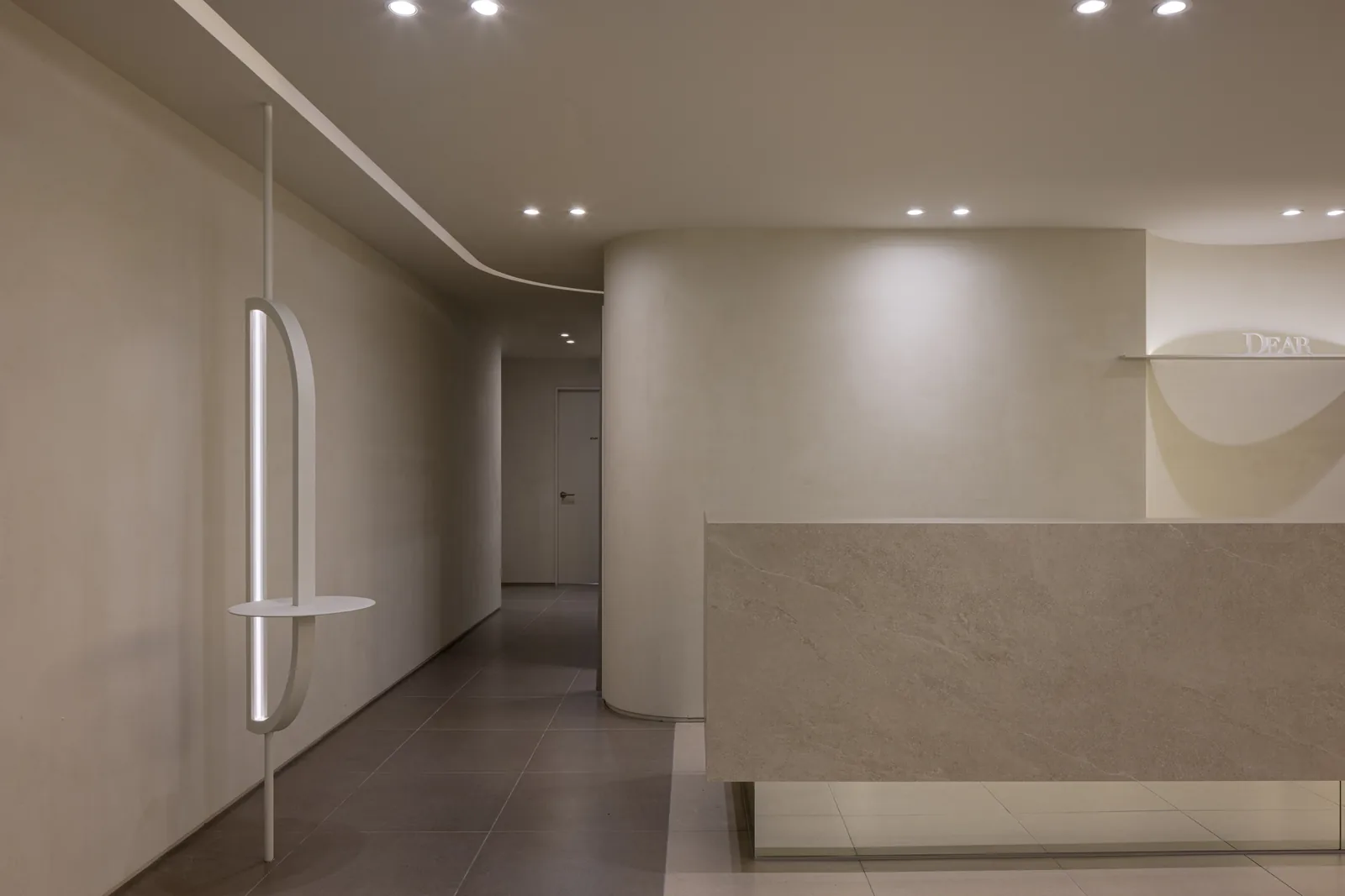 Reception seen from the opposite angle with the arc floor lamp at Dear Clinic Cheongdam