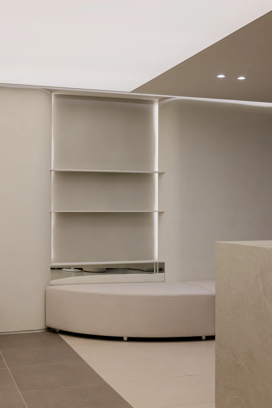 Curved shelving niche with a round bouclé ottoman at Dear Clinic Cheongdam
