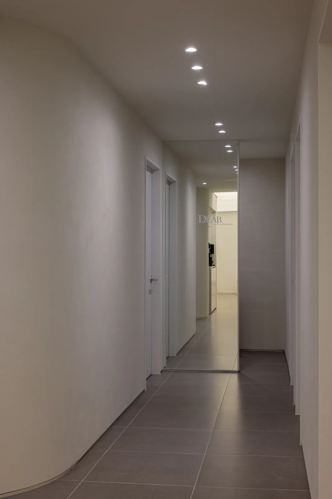 Treatment corridor with a mirrored end wall reflecting the DEAR clinic logo