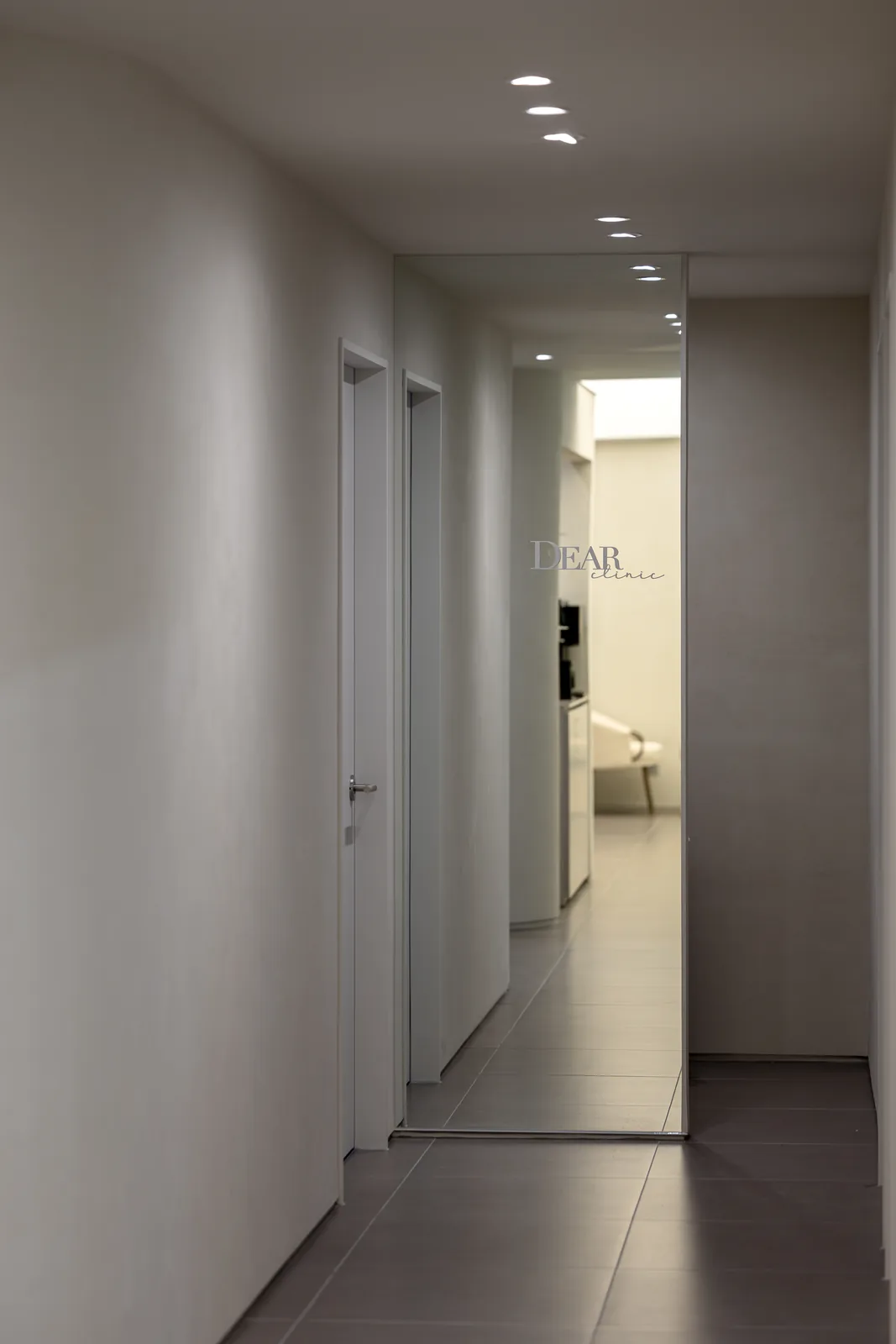 Treatment corridor at Dear Clinic Cheongdam, with the clinic logo reflected in a full-height mirror
