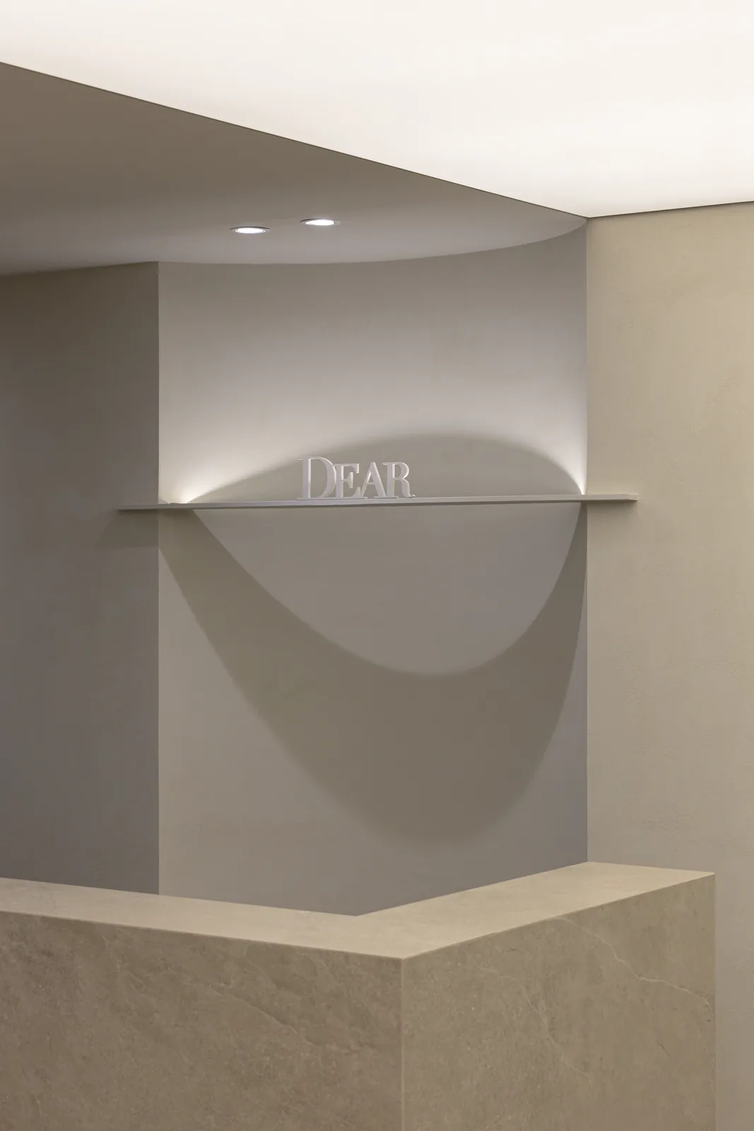 The DEAR Clinic brand sign lit on a curved plaster wall above the reception counter