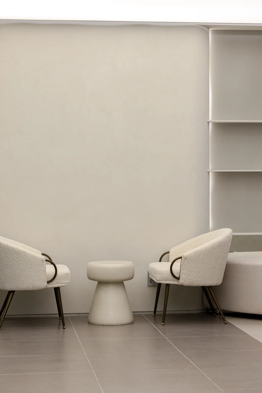 Two bouclé armchairs and a stone stool in the waiting area at Dear Clinic Cheongdam