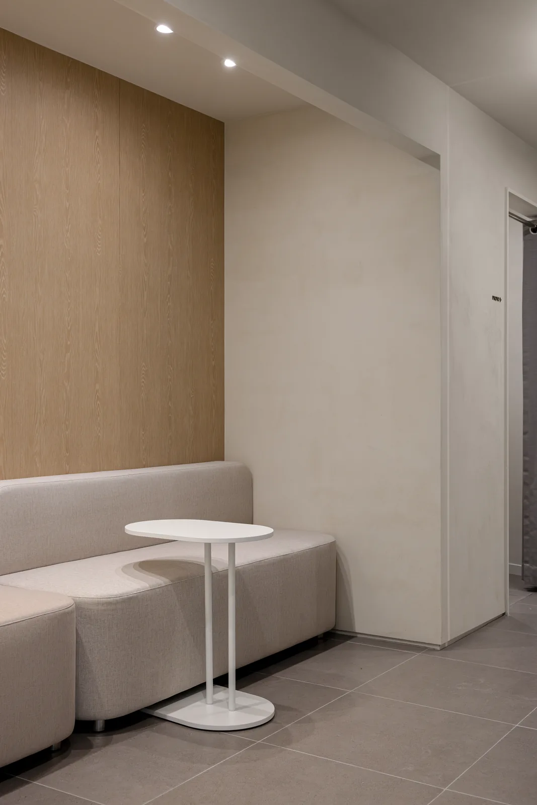 Backlit arch mirror with the DEAR mark above a recovery bed at Dear Clinic Cheongdam