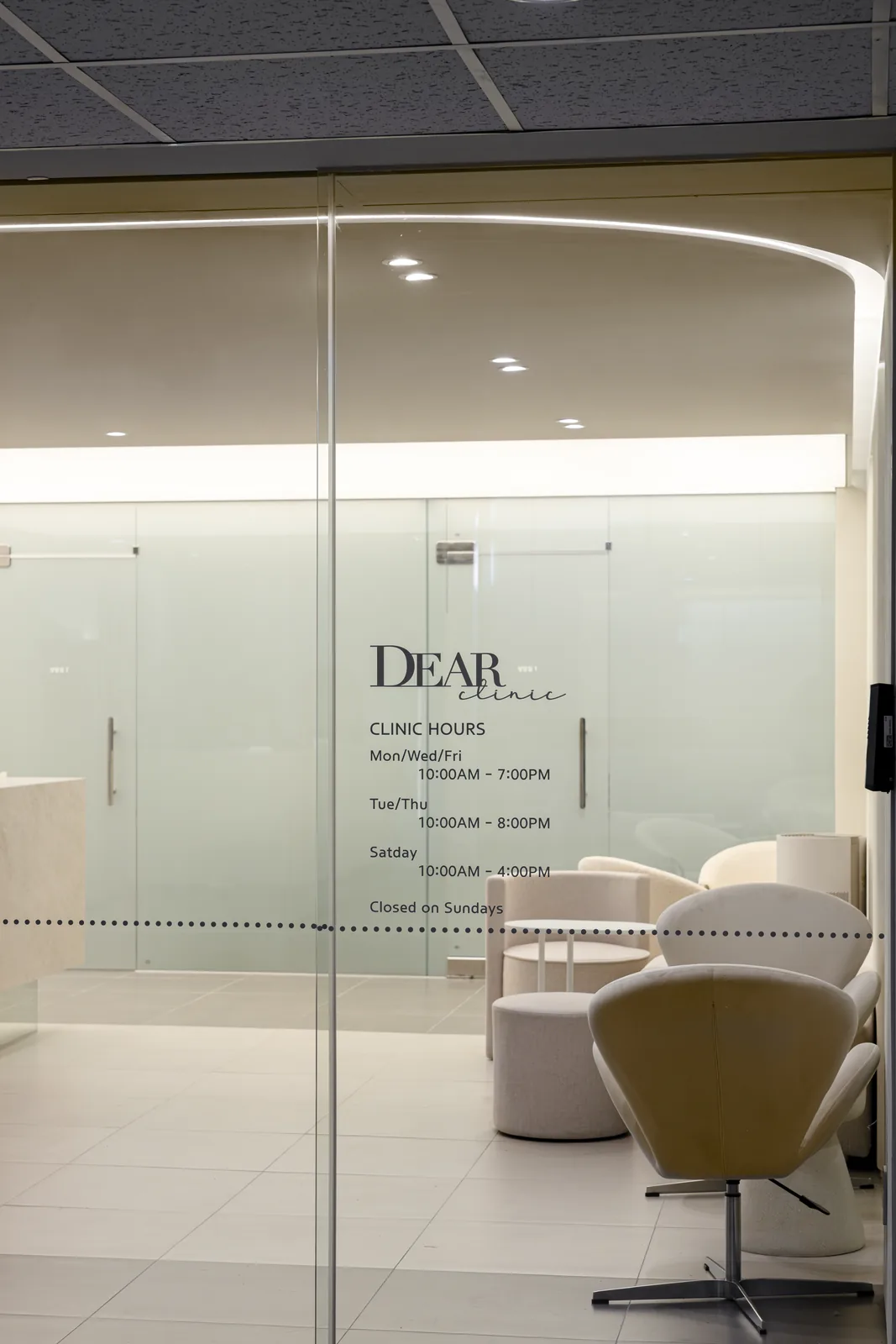 Entrance of Dear Clinic in Cheongdam, Gangnam, Seoul, with the clinic hours shown in English on the glass door