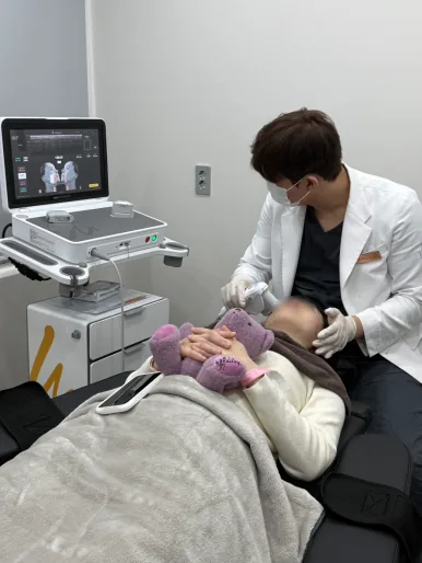 Doctor applying the Ultherapy Prime transducer during a focused ultrasound session at Dear Clinic Cheongdam