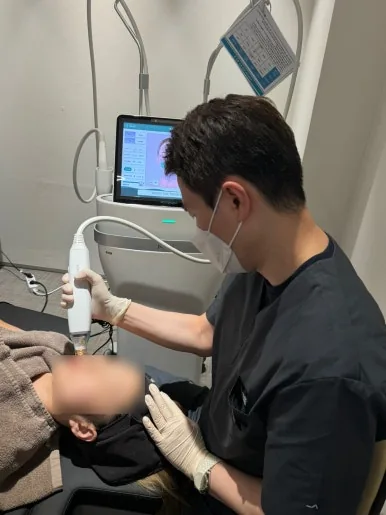 Doctor working a lifting handpiece across the mid-face at Dear Clinic Cheongdam